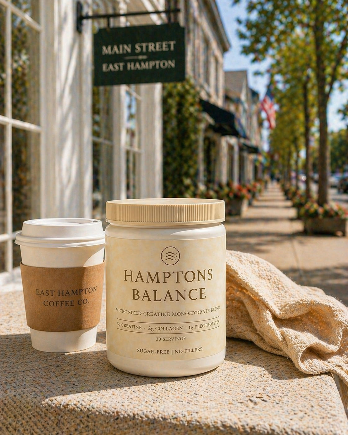 Hamptons Balance product and East Hampton Coffee Co. cup on a table with a street scene in the background